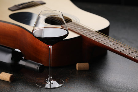 Acoustic guitar and red wine on black table, closeupの写真素材