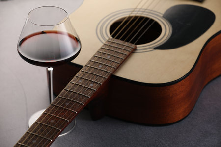 Acoustic guitar and red wine on gray table, closeupの写真素材