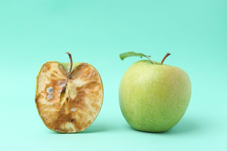 Spoiled apple and good ones on turquoise backgroundの写真素材