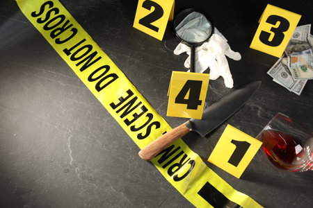 Forensic expert. Yellow crime scene tape, markers and evidence on black table, above view. Space for textの写真素材
