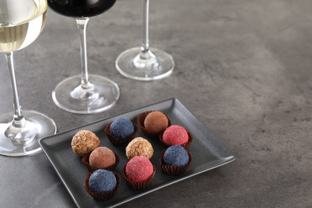 Tasty truffle bonbons and wine on gray table, above view. Space for textの写真素材