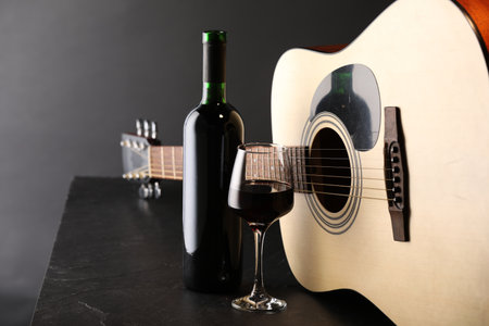 Acoustic guitar and red wine on black table, closeupの写真素材