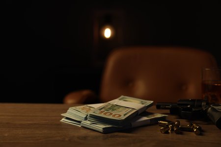 Gun, bullets and money on wooden table in mafia boss office. Space for text