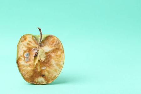 Half of spoiled apple on turquoise background. Space for text