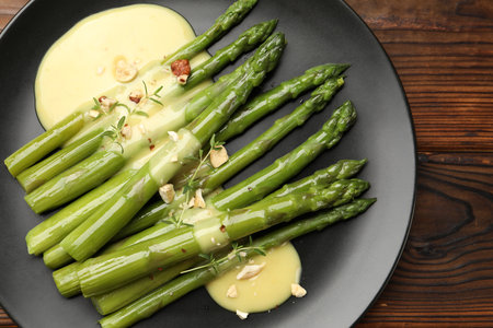Tasty cooked asparagus served with sauce on wooden table, top viewの写真素材