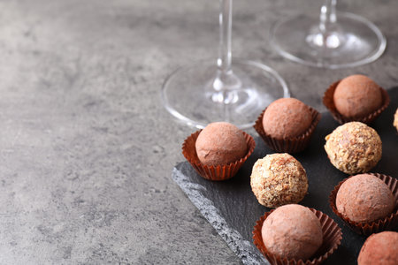 Tasty truffle bonbons on gray textured table, closeup. Space for textの写真素材