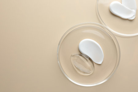 Different cosmetic products in Petri dishes on beige background, flat lay. Space for textの写真素材