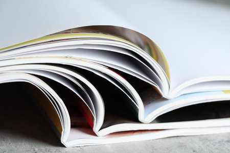 Different open magazines on gray table, closeup