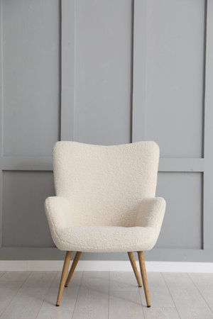 Comfortable beige armchair near light gray wall indoorsの写真素材