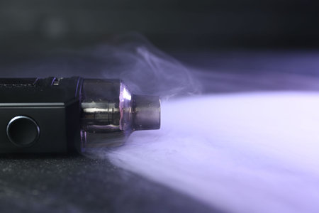 Modern electronic smoking device on black table, closeup. Space for text