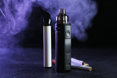 Electronic smoking devices and cigarettes on black tableの写真素材