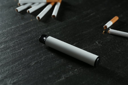 Electronic smoking device and cigarettes on black table, closeupの写真素材