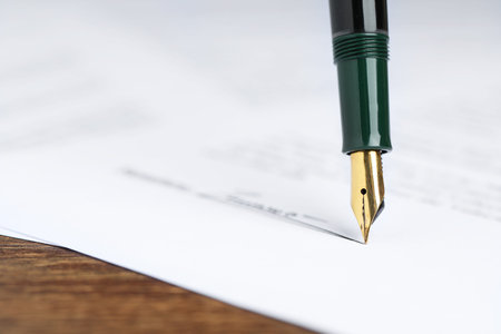 Signing notary document with fountain pen at wooden table, closeup