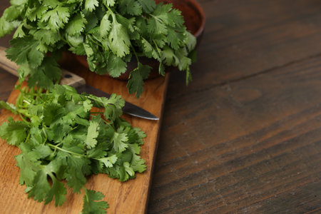 Cutting board with fresh cilantro and knife on wooden table, closeup. Space for textの写真素材