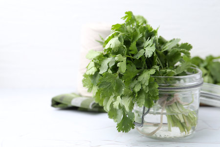 Fresh aromatic cilantro in jar on white table, closeup. Space for textの写真素材