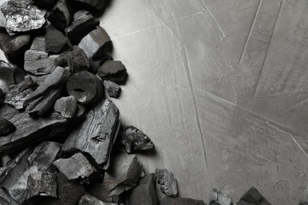 Pieces of black coals on gray table, flat lay. Space for text
