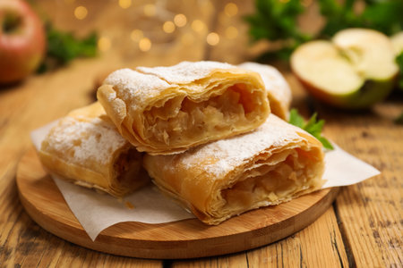 Pieces of tasty apple strudel with powdered sugar on wooden table, closeupの写真素材