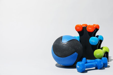Medicine ball and dumbbells on light gray background, space for textの写真素材