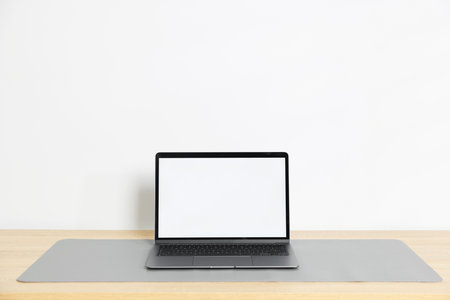Stylish workplace with laptop and gray mousepad on wooden table indoors. Space for textの写真素材