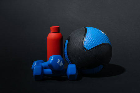 Medicine ball, dumbbells and water bottle on black backgroundの写真素材