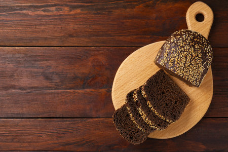 Pieces of fresh rye bread with seeds on wooden table, top view. Space for text