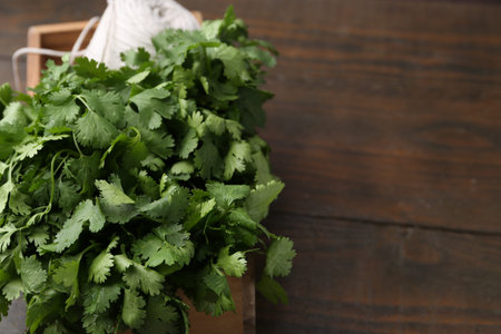 Fresh aromatic cilantro and thread in crate on wooden table, closeup. Space for text