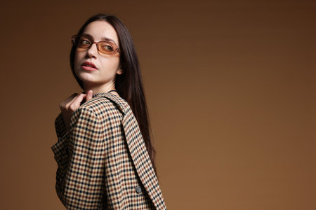 Portrait of beautiful woman in stylish outfit on brown background, space for textの写真素材