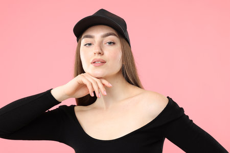 Portrait of beautiful woman in stylish baseball hat on pink backgroundの写真素材
