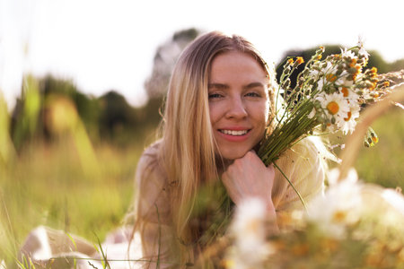 Beautiful woman with wildflowers in meadow on sunny dayの写真素材