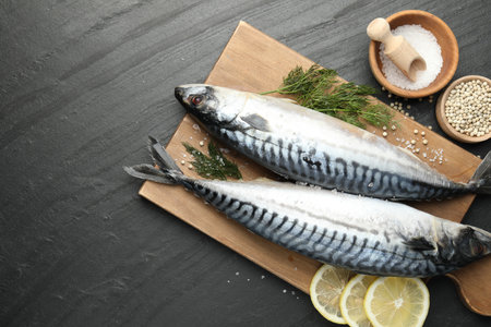 Seafood delicacies. Fresh raw mackerels and spices on black table, flat lay. Space for textの写真素材