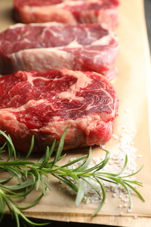 Pieces of raw beef meat, rosemary and salt on table, closeupの写真素材