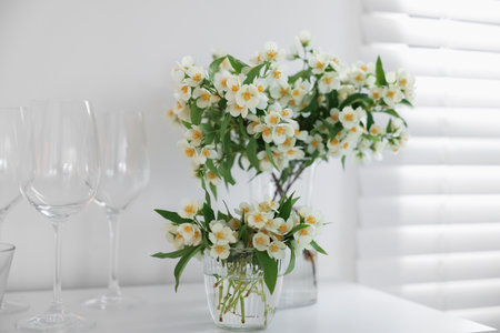 Bouquet of beautiful jasmine flowers in vase on white table indoorsの写真素材