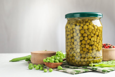 Tasty pickled peas in jar and ingredients on white table, closeupの写真素材