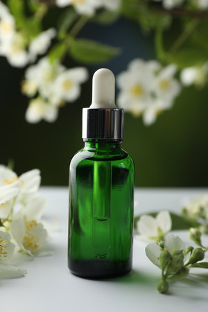 Essential oil and jasmine flowers on white table against blurred background, closeupの写真素材