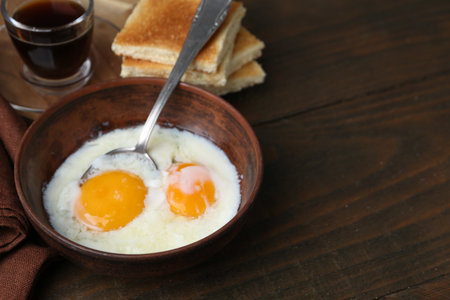 Traditional asian breakfast with half-boiled eggs in bowl, soy sauce and toasted bread on wooden table, closeup. Space for textの写真素材