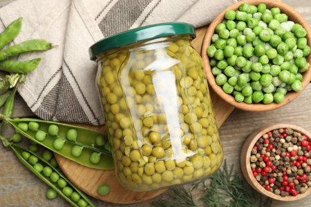 Pickled peas in jar, spices, dill and pods on wooden table, flat layの写真素材