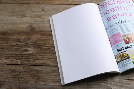 Open magazine on wooden table. Mockup for designの写真素材