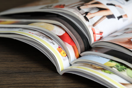 Different open magazines on wooden table, closeupの写真素材