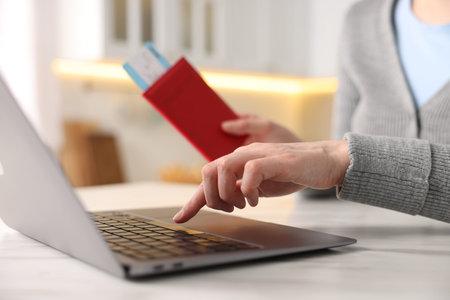 Woman with passport and flight ticket using laptop at white marble table indoors, closeupの写真素材