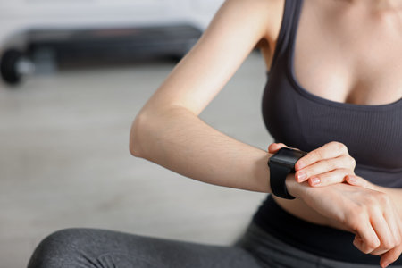 Woman checking fitness tracker during training indoors, closeup