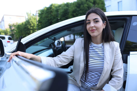Woman getting out of modern car outdoors