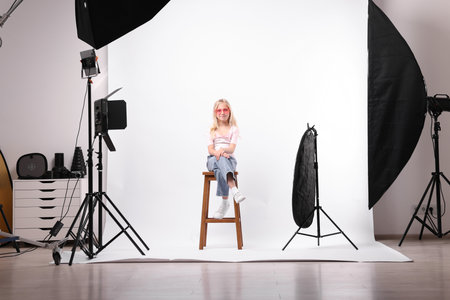 Little girl on white background in photo studio with professional equipmentの写真素材