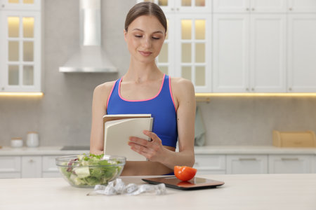 Woman developing diet plan at white table indoorsの写真素材
