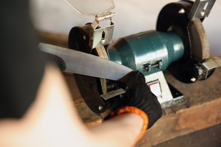 Man sharpening knife with bench grinder indoors, closeupの写真素材
