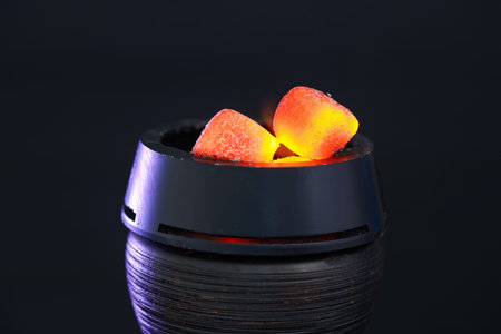 Smoldering charcoal cubes in hookah holder and smoke on dark background, closeup