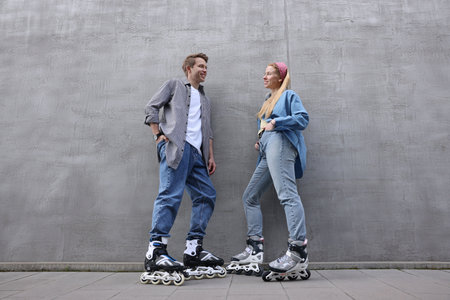 Happy couple with roller skates near gray wall outdoors, low angle viewの写真素材