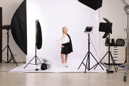 Little girl on white background in photo studio with professional equipmentの写真素材