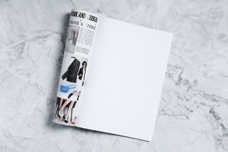Open magazine on white marble background, top view. Mockup for designの写真素材
