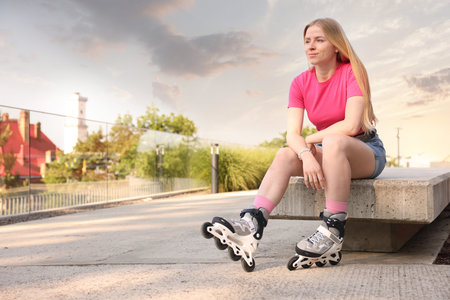 Happy woman with roller skates on street. Space for text