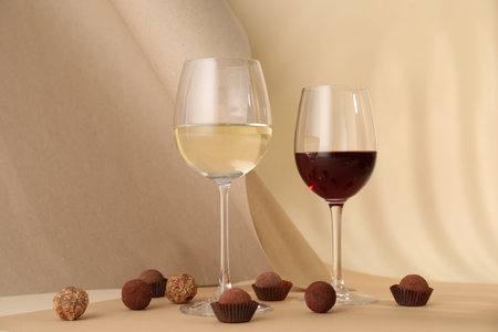 Delicious truffle bonbons and wine on beige background